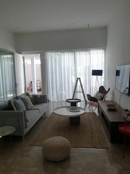 Living features: grey fabric sofa, decorative cushions, round coffee table, wooden TV console, wall-mounted TV, area rug, floor-to-ceiling windows, sheer curtains, decorative floor lamp, wooden accent chair, woven pouf, light-colored walls, polished concrete flooring; style: modern.