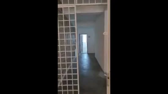 Room features: white painted walls, concrete flooring, metal grille door, doorway leading to another room, neutral color scheme, minimalist design; style: minimalist.