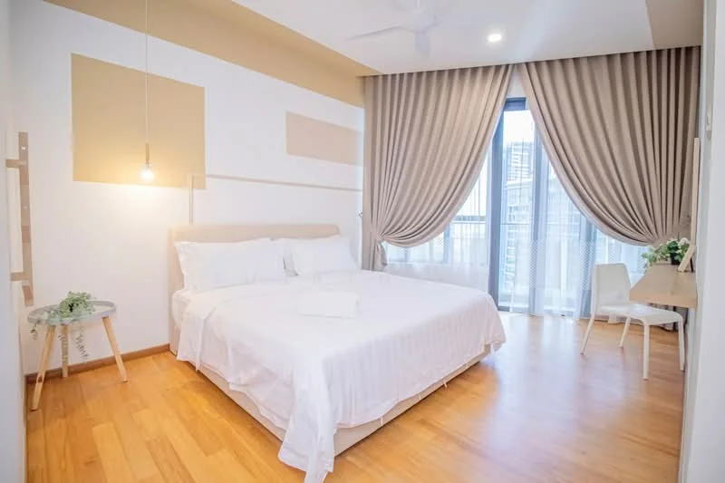 Bedroom features: queen-size bed with white bedding, wooden flooring, floor-to-ceiling windows, sheer curtains, drapes, wall-mounted light fixture, ceiling fan, study desk, white chair, decorative plant on side table; style: modern; view: city.