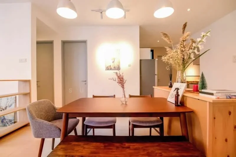 Dining features: wooden dining table, 4 wooden dining chairs, grey upholstered chair, pendant lighting with three bulbs, white painted walls, light wood cabinetry, decorative vase with dried flowers, framed artwork on wall, refrigerator visible in background, open shelving unit, neutral flooring; style: modern.