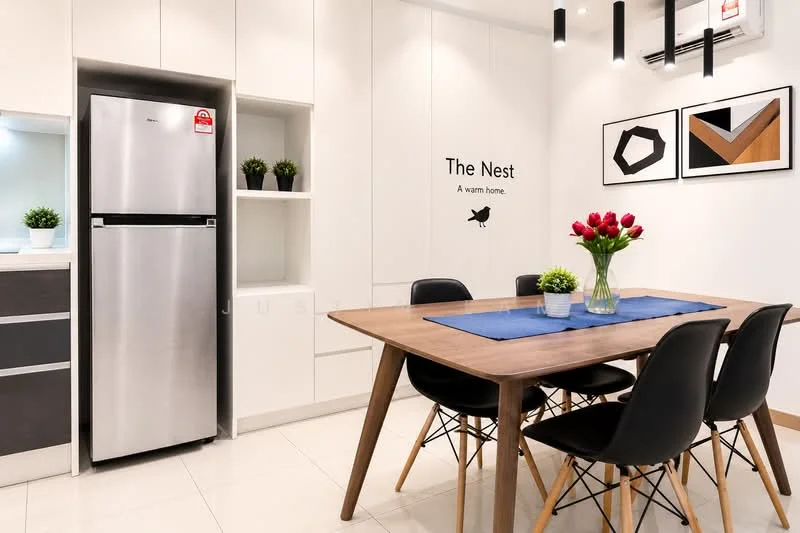 Dining features: wood dining table, 4 black dining chairs, blue table runner, vase with red tulips, wall-mounted artwork, white cabinets, built-in shelving, stainless-steel fridge, wall-mounted air conditioning unit, light fixtures with black pendant lights, cream tiled flooring, decorative wall text; style: modern.