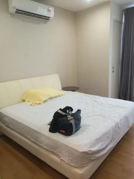 Bedroom features: queen-size bed with white upholstered frame, light yellow throw pillow, wooden bedside table, curtains, wall-mounted split AC unit, laminate flooring, neutral painted walls, door to hallway; style: modern.