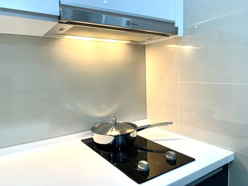 Kitchen features: white cabinetry, stainless-steel range hood, black glass cooktop, silver knobs on cooktop, white countertop, grey backsplash, pan with lid on cooktop, under-cabinet lighting; style: modern.