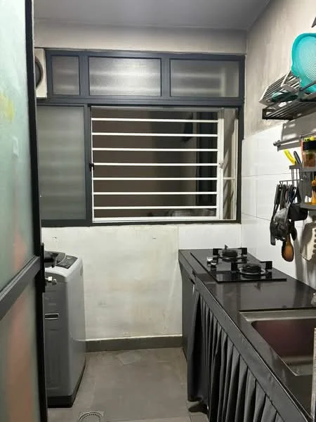 Kitchen features: black countertop, stainless-steel sink, 2-burner gas hob, grey cabinetry, white tiled backsplash, washing machine, window with security bars, grey floor tiles, wall-mounted storage rack, kitchen utensils hanging, overhead cabinets; style: modern.