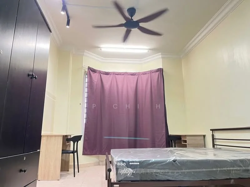 Bedroom features: single bed, mattress on bed frame, black wardrobe, wooden study desk, black chair, purple curtain, ceiling fan, light fixture, cream painted walls, tile flooring.
