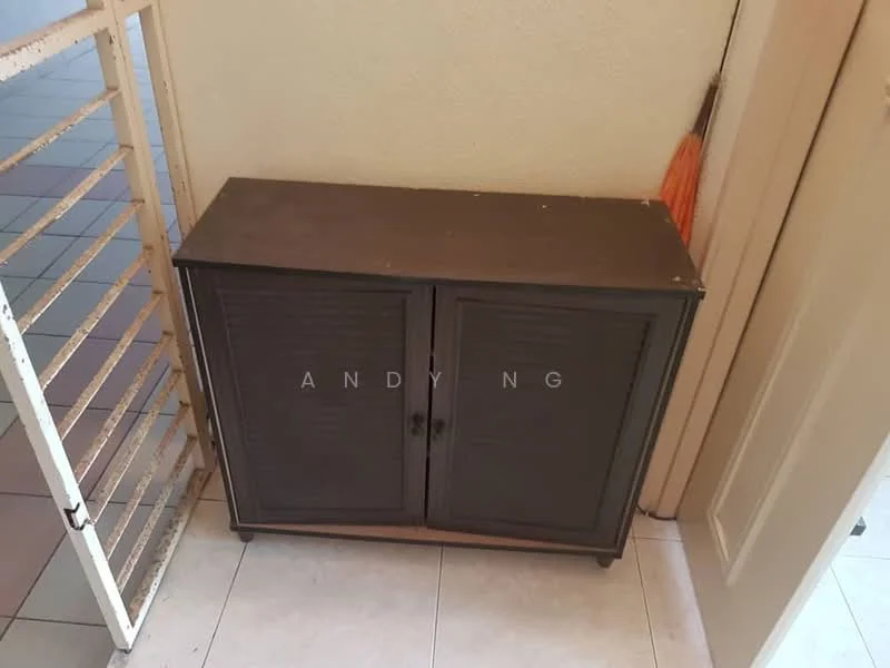 Room features: brown wooden cabinet with two doors, metal handles, floor tiles in light color, wall with painted finish, corner placement, visible door frame, metal railing, umbrella visible next to cabinet.
