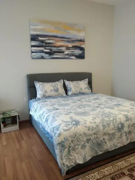 Bedroom features: king-size bed with upholstered headboard, blue floral bedding, two decorative pillows, wooden flooring, framed artwork above the bed, nightstand with plant, area rug with intricate pattern, neutral painted walls; style: modern.