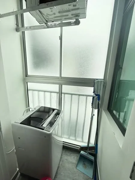 Laundry features: top-load washing machine, window with frosted glass, grey tile flooring, balcony access, cleaning broom, mop, white walls, metal railing.