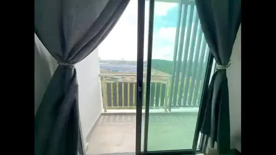 Room features: sliding glass door, floor-to-ceiling windows, grey curtains, balcony view, concrete flooring, white walls.