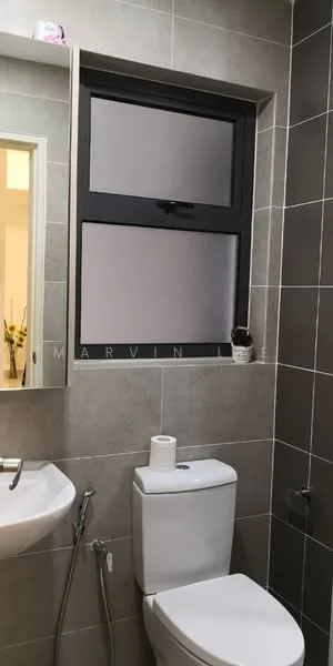 Bathroom features: grey tiled walls, light grey tiled flooring, white toilet, chrome toilet paper holder, sink with chrome faucet, mirror above sink, window with frosted glass, decorative plant on window sill; style: modern.