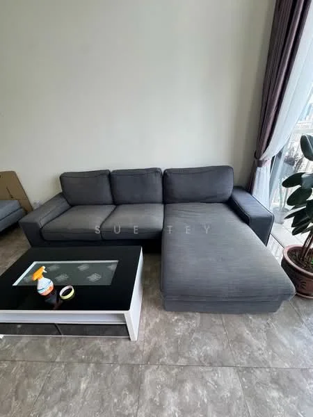Living features: L-shape sectional sofa in grey, coffee table with black top and white base, ceramic tile flooring, large window with sheer curtains, potted plant, neutral painted walls, decorative wall art, cleaning spray bottle on table; style: modern.