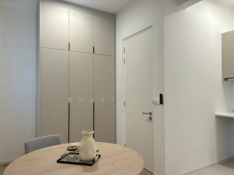 Room features: light beige cabinetry, white walls, round dining table, grey upholstered chair, decorative vase, black serving tray, door with modern handle, minimalist design; style: modern.
