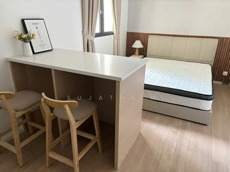 Bedroom features: queen-size bed, upholstered headboard, wooden flooring, white walls, wood paneling, table lamp, framed artwork, breakfast bar with two stools; style: modern.
