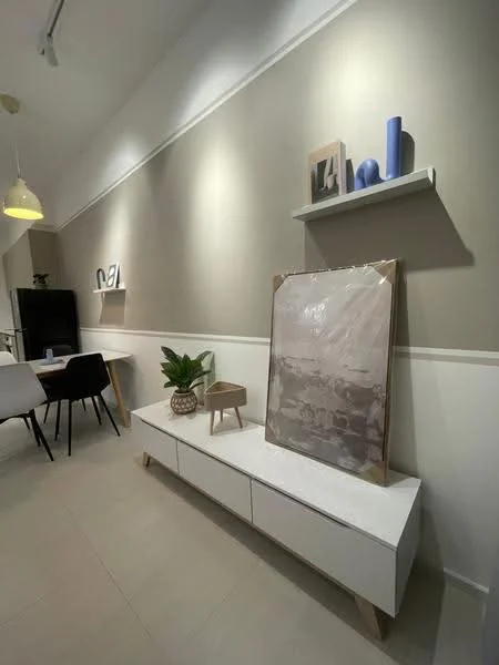 Living features: light grey painted walls, white wainscoting, white console table with wooden legs, framed artwork on console, decorative plant in ceramic pot, shelf with decorative items, pendant light fixture, tile flooring in light beige; style: modern.