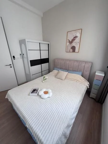Bedroom features: king-size bed with upholstered headboard, white bedspread with textured pattern, decorative pillow, framed artwork on wall, built-in wardrobe with sliding doors, wooden flooring, small plant on bedside, magazine on bed; style: modern.