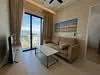 Living features: beige fabric sofa, glass coffee table, floor-to-ceiling windows, sheer curtains, ceiling fan, light-colored walls, decorative artwork on wall, tile flooring; style: modern; view: city.