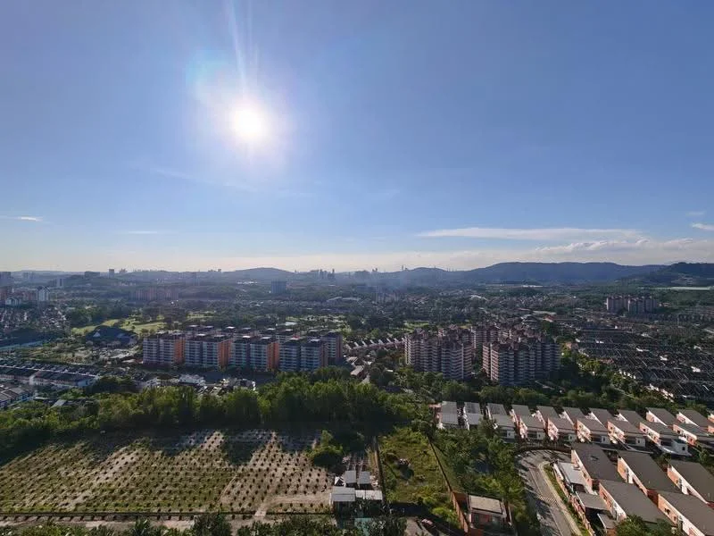 Exterior type: high-rise condominium; features: city skyline view, surrounded by greenery, residential buildings in foreground, mountainous backdrop, clear blue sky, sunlight glare; style: modern.