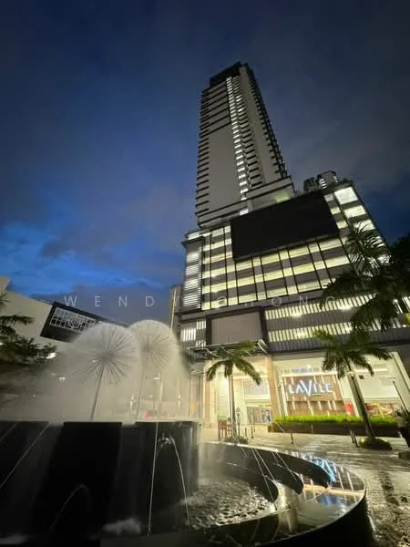 Exterior type: high-rise condominium; features: glass curtain wall, illuminated facade, water fountain feature, manicured landscaping, palm trees, outdoor seating area, modern architectural design, multiple storeys, night lighting, surrounding urban context; style: modern.