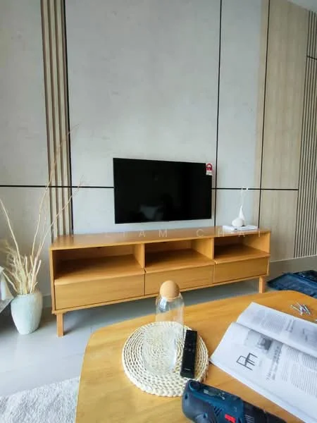 Living features: light wood TV console with open shelving, wall-mounted flat-screen TV, decorative vase with dried plants, round woven placemat, glass decorative item, coffee table, neutral wall with vertical wood paneling, light-colored flooring, magazine or brochure on the table, screwdriver on the table; style: modern.
