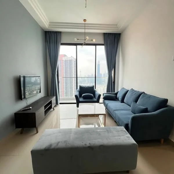 Living features: grey painted walls, white ceiling with crown moulding, floor-to-ceiling windows, blue fabric 3-seater sofa, blue fabric armchair, white coffee table, TV console in dark wood, wall-mounted TV, marble tile flooring, chandelier with multiple bulbs, curtains in light grey, decorative wall art; style: modern; view: city.