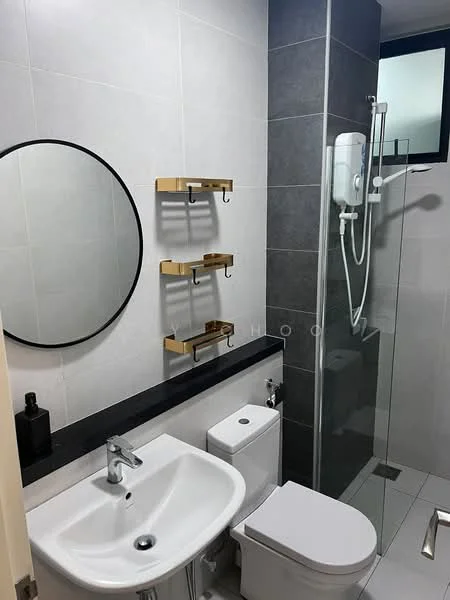 Bathroom features: grey tiled walls, white ceramic sink, chrome basin mixer faucet, round framed mirror, black countertop, white toilet, shower with glass enclosure, wall-mounted showerhead, shower control panel, gold wall-mounted storage shelves, white tiled flooring, black accent wall; style: modern.