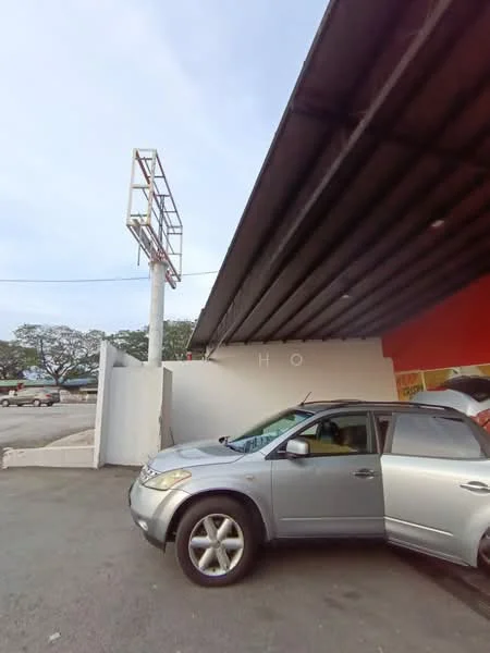 Exterior features: metal roof, red painted facade, signage structure, paved parking area, one parked car, surrounding trees, open space, clear sky; style: modern.