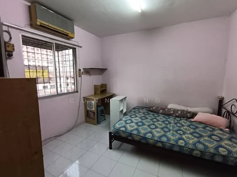 Bedroom features: pink painted walls, white tiled flooring, single bed with patterned bedding, wooden wardrobe, study desk, window with metal grille, wall-mounted air conditioning unit, shelf unit, light fixture on ceiling.