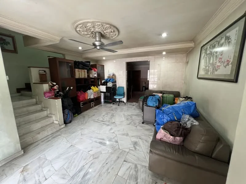Living features: marble tile flooring, cream painted walls, exposed ceiling with decorative plaster, 5-blade ceiling fan, sofa in brown leather, wooden shelving unit, various bags and boxes, staircase leading to upper level, natural light from windows, decorative artwork on wall; style: traditional.
