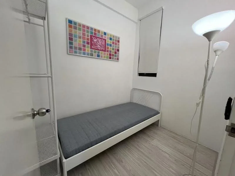 Bedroom features: single bed frame with mattress, white painted walls, light wood laminate flooring, framed artwork on wall, floor lamp, window with roller blinds; style: minimalist.