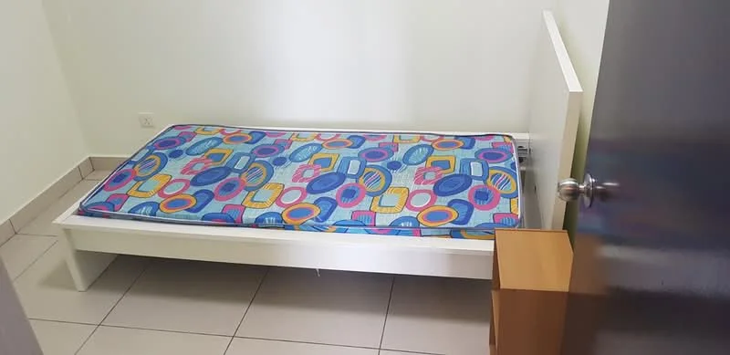 Bedroom features: single bed frame, mattress with colorful patterned bedding, light-colored walls, tiled flooring, wooden bedside table, door leading to hallway.