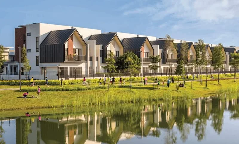Exterior type: linked terrace house; features: white painted facade, black metal roofing, large windows, balconies on upper floors, manicured lawn, landscaped garden, pond with reflection, surrounding greenery, walking path, outdoor seating areas, children playing area; style: modern.