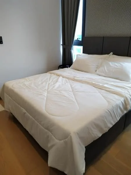 Bedroom features: king-size bed with white bedding, upholstered headboard, wooden flooring, floor-to-ceiling window with grey curtains, nightstand, wall-mounted light switch, decorative wall paneling; style: modern.