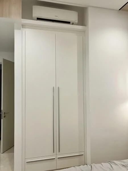 Room features: white built-in wardrobe with double doors, silver handles, wall-mounted split AC unit, neutral wall colour, light-coloured flooring; style: modern.