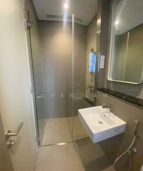Bathroom features: glass shower enclosure, rain shower head, handheld shower, wall-mounted faucet, white wall-mounted sink, mirror with rounded edges, grey tiled walls, light grey floor tiles, recessed lighting, chrome towel rail; style: modern.