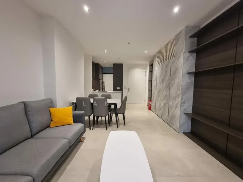 Living features: grey fabric sofa, yellow accent pillow, white coffee table, dining table for 4, 4 grey dining chairs, light grey tiled flooring, recessed downlights, wall-mounted shelving unit, open layout to kitchen, neutral painted walls; style: modern. Room features: grey cabinetry, marble accent wall, kitchen area visible in background.