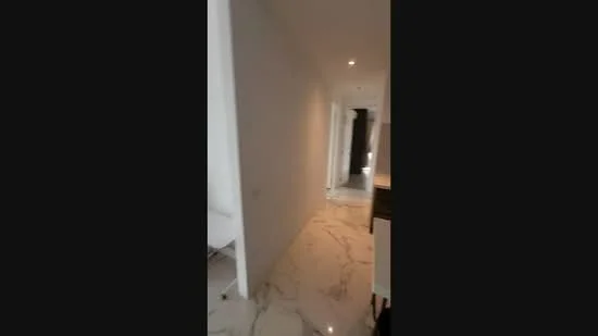 Room features: marble tile flooring, white painted walls, recessed downlights, doorway leading to another room, hallway layout, neutral color palette; style: modern.