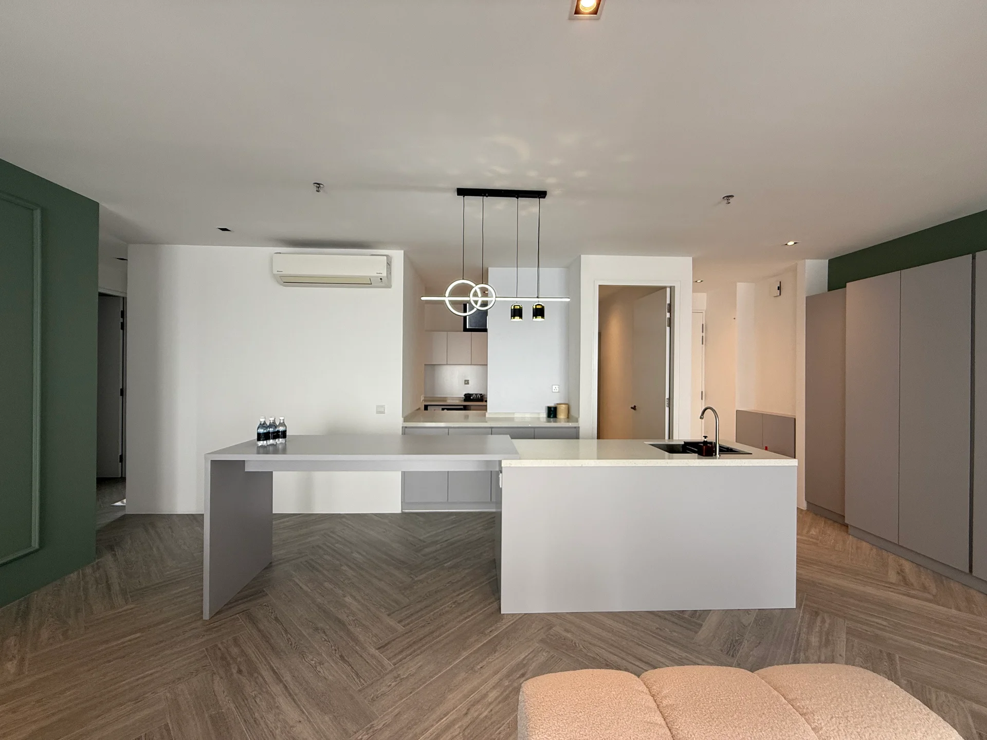 Kitchen features: grey cabinetry, white countertop, single-bowl stainless-steel sink, chrome pull-down faucet, built-in oven, freestanding range oven, recessed LED downlights, pendant lighting, open shelving, air conditioning unit, herringbone patterned flooring; style: modern.