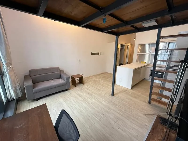 Living features: grey fabric sofa, wooden flooring, white painted walls, exposed wooden ceiling, large windows with sheer curtains, open layout to kitchen, wooden staircase, dining table with black chair; style: modern. Kitchen features: white cabinetry, kitchen island, stainless-steel appliances, open shelving, countertop with bar seating; style: modern.