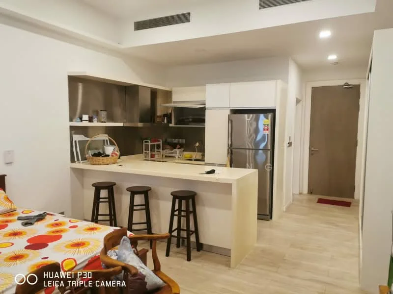 Kitchen features: white cabinetry, stainless-steel fridge, built-in oven, 4-burner gas hob, stainless-steel range hood, white countertop, bar seating with 3 stools, tile backsplash, open shelving, microwave, ceramic tile flooring, recessed downlights; style: modern. Room features: bed with colorful bedding, wooden chair, wooden table, laminate flooring.