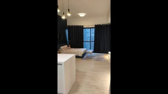 Room features: light wood flooring, black curtains, sofa, coffee table, wall-mounted light fixtures, ceiling light fixture, large window, neutral wall color; style: modern; view: city.