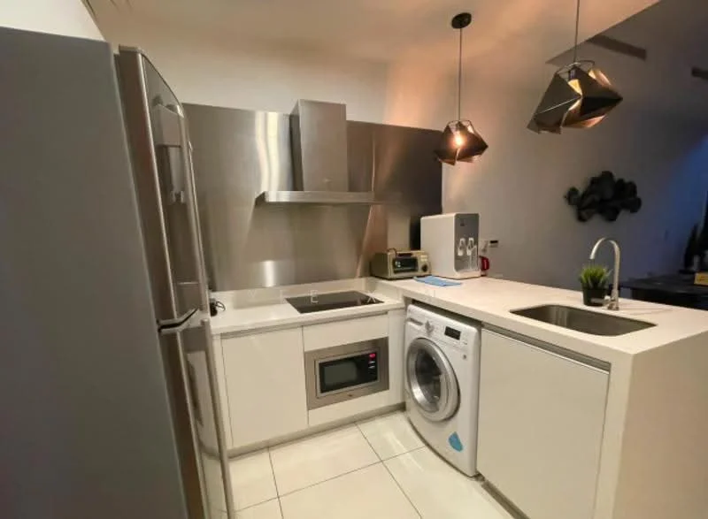 Kitchen features: stainless-steel refrigerator, stainless-steel range hood, built-in microwave, single-bowl stainless-steel sink, chrome pull-down faucet, white cabinetry, white countertop, front-load washing machine, pendant lighting, ceramic tile flooring, wall-mounted decor; style: modern.