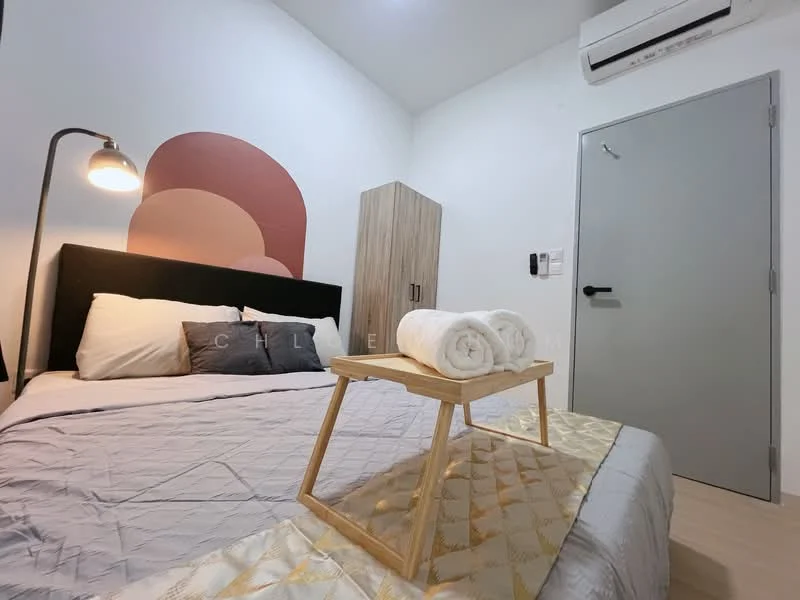 Bedroom features: queen-size bed, upholstered headboard, bedding in neutral tones, decorative throw pillows, wooden bedside lamp, wooden tray on bed, towels neatly arranged on tray, light wood flooring, wall-mounted air conditioning unit, painted accent wall in warm tones, built-in wardrobe, grey wall with minimal decor, white painted walls; style: modern.