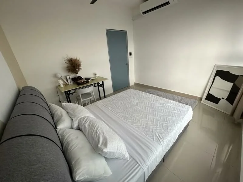 Bedroom features: king-size bed with grey upholstered headboard, white bedding with textured pattern, study desk with chair, wall-mounted air conditioning unit, white painted walls, glossy tile flooring, decorative plant in vase, framed artwork leaning against wall; style: modern.