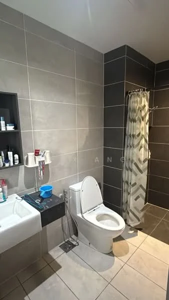 Bathroom features: white toilet, single-sink vanity with wall-mounted cabinet, chrome basin mixer faucet, grey tile walls, cream tile flooring, shower area with glass partition, shower curtain with geometric pattern, built-in shelving for toiletries; style: modern.