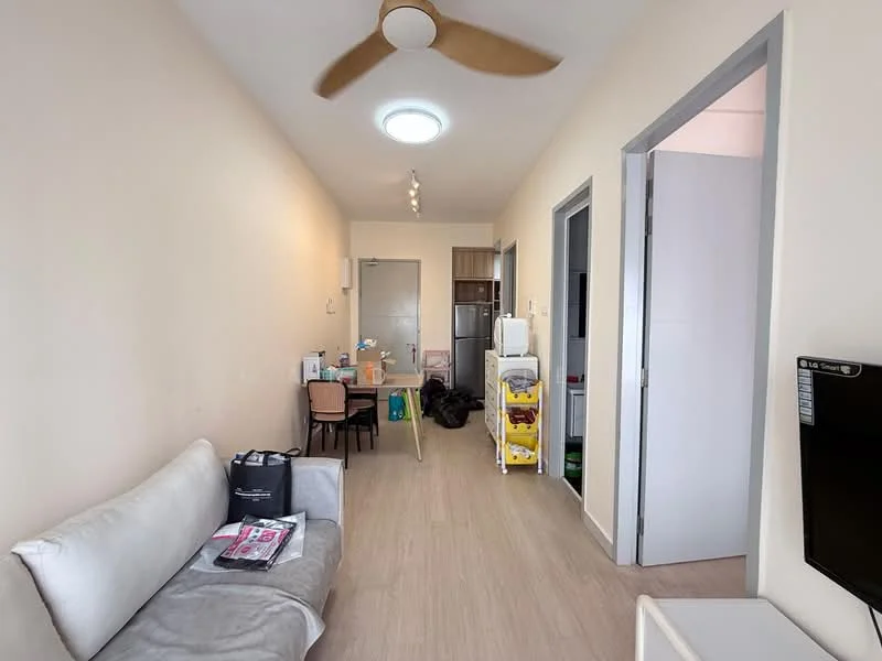Living features: light wood laminate flooring, beige painted walls, 5-blade ceiling fan, recessed ceiling lights, sofa in light grey fabric, wall-mounted TV, small dining table with chairs, open layout, doorway leading to kitchen, doorway leading to bedroom, storage cart, decorative items on table; style: modern.