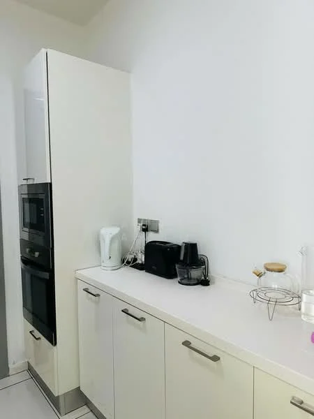 Kitchen features: white cabinetry, stainless-steel handles, built-in oven, built-in microwave, white kettle, black coffee machine, black toaster, white countertop, tile flooring, wall-mounted electrical outlets; style: modern.