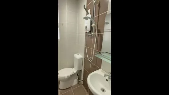 Bathroom features: white tiled walls, brown accent wall, ceramic tile flooring, one-piece toilet, chrome basin mixer faucet, framed mirror, shower with handheld showerhead, glass shelf; style: modern.