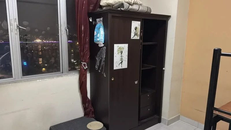 Room features: brown wooden wardrobe with shelves, grey upholstered bench, floor-to-ceiling window, curtains in dark red, white tiled flooring, beige painted walls, decorative artwork on wardrobe, city view from window; style: modern; view: city.