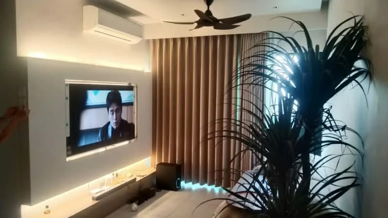 Bedroom features: wall-mounted TV, 5-blade ceiling fan, curtains, large window, indoor plant, lighted feature wall, bed with bedding, wooden flooring, air conditioning unit; style: modern.