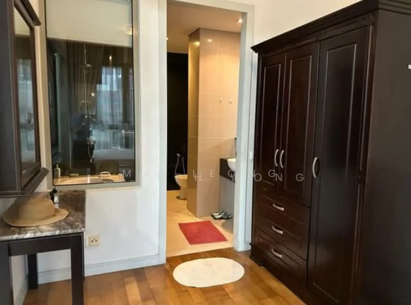 Room features: dark wood wardrobe, mirror on wall, light wood flooring, white walls, bathroom door visible, red bath mat, round area rug, countertop with decorative item; style: modern.